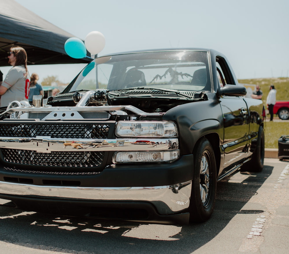 Black Silverado with the hood off at a car show