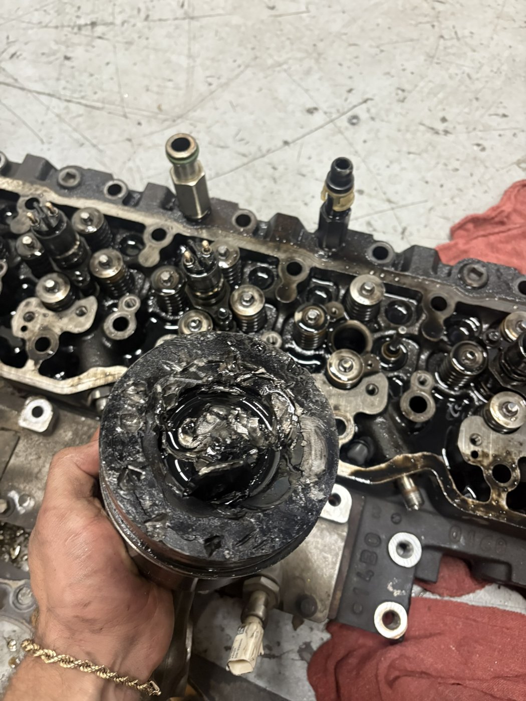 Damaged piston held over a cylinder head during a teardown