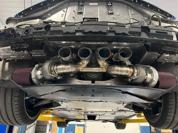 Twin turbo system under the rear of a C8 Corvette on a lift